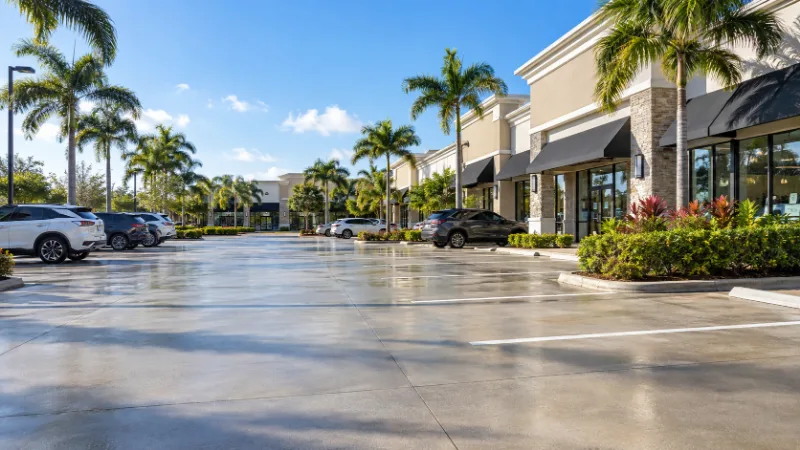A retail plaza parking lot, the paving washed clean between marked stalls.